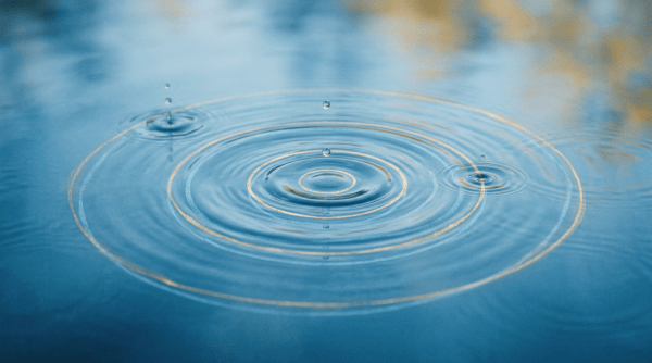 Water droplets creating concentric ripples on a blue surface